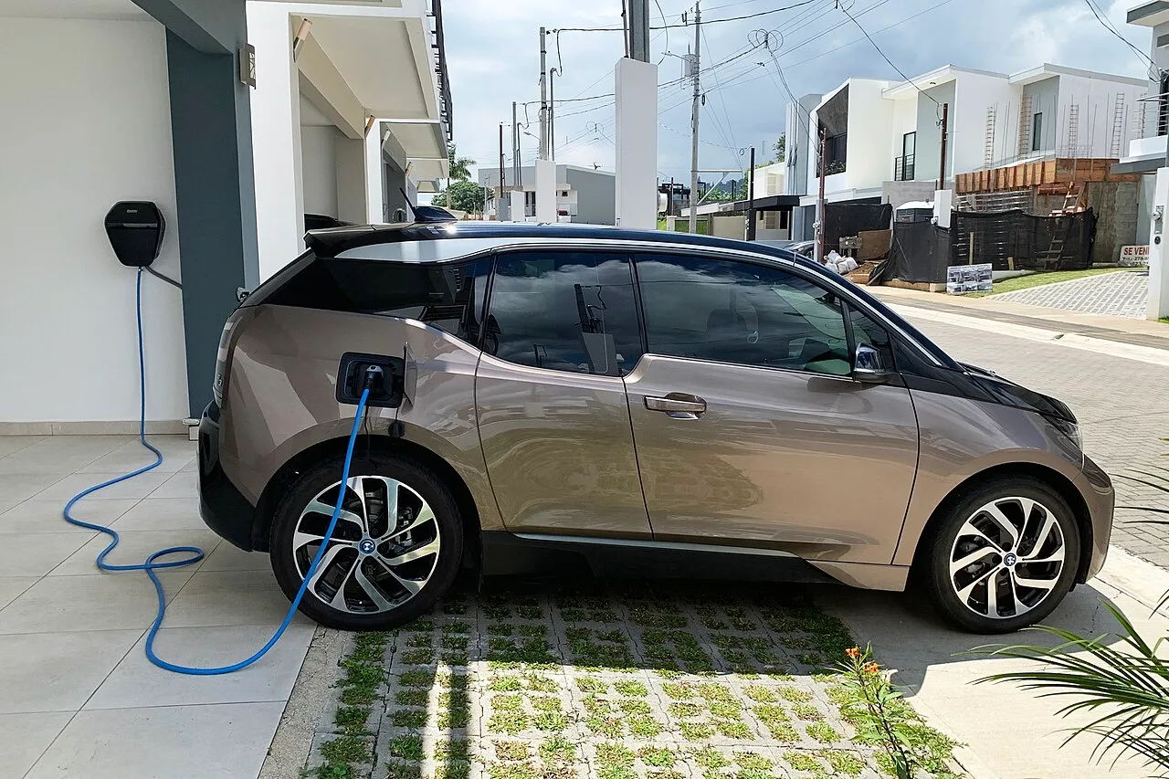 Home EV charging station: Level 2 wall charger plugged into an electric car in a driveway