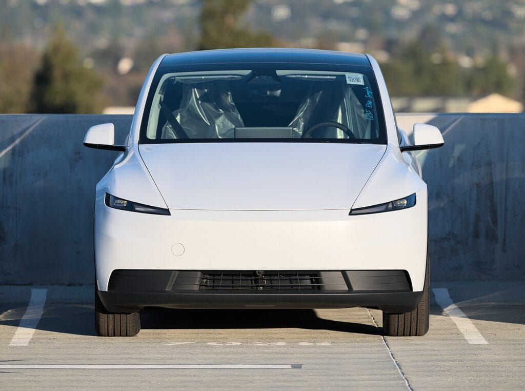 White Tesla Model Y electric SUV, front view, 2026