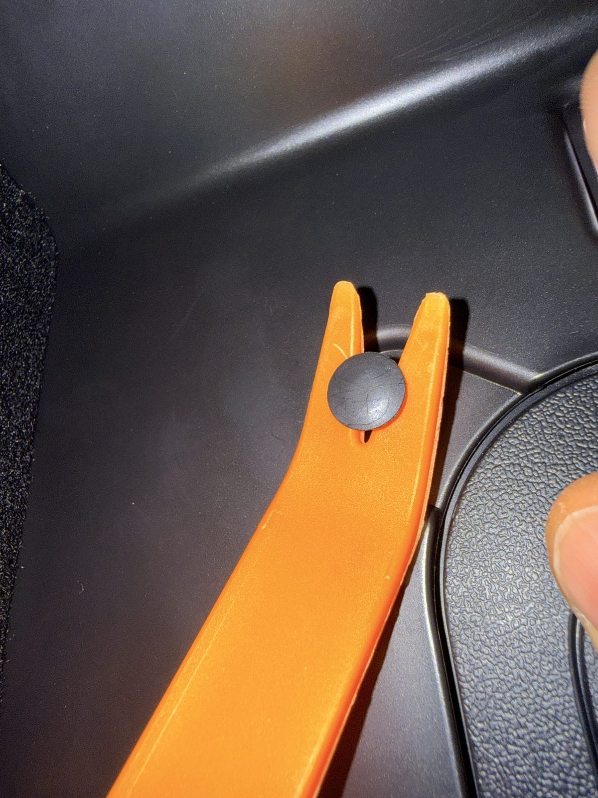 Removing a push pin from the Model Y under-glovebox cover with a trim tool