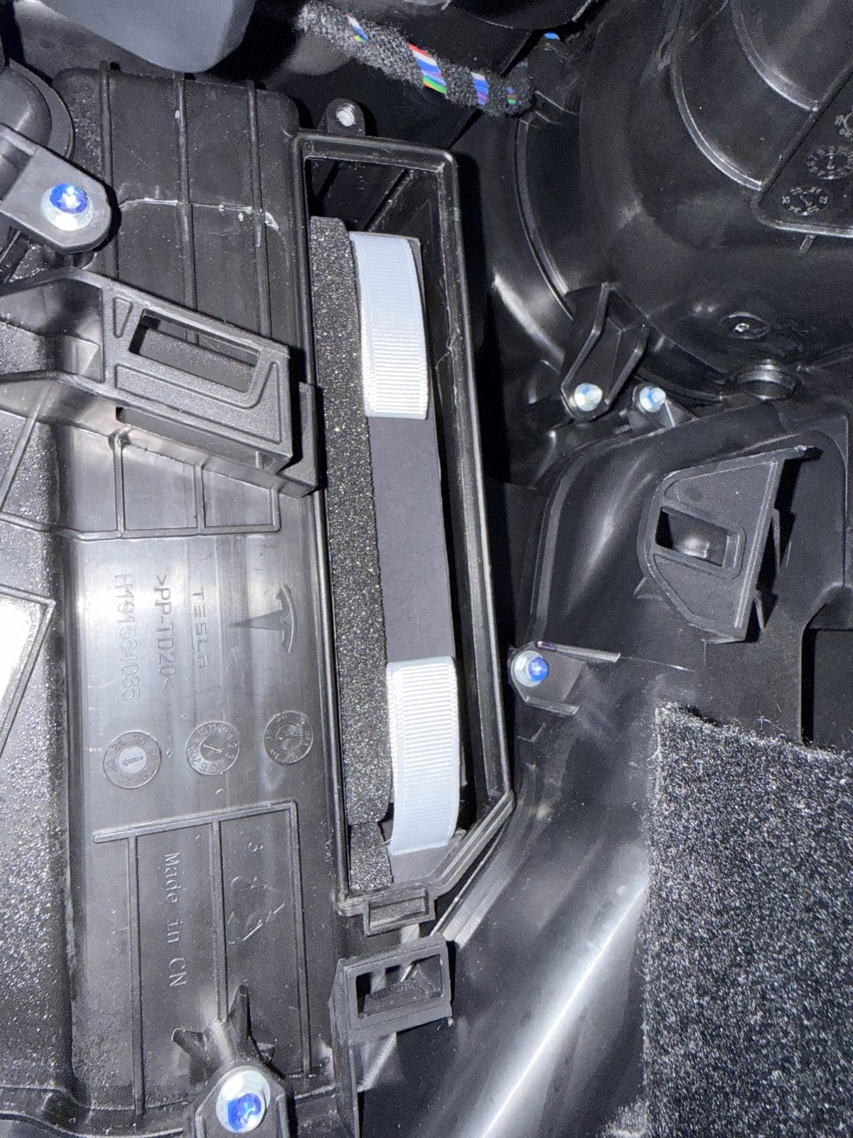 Old Tesla Model Y cabin air filters with pull tabs visible in the housing