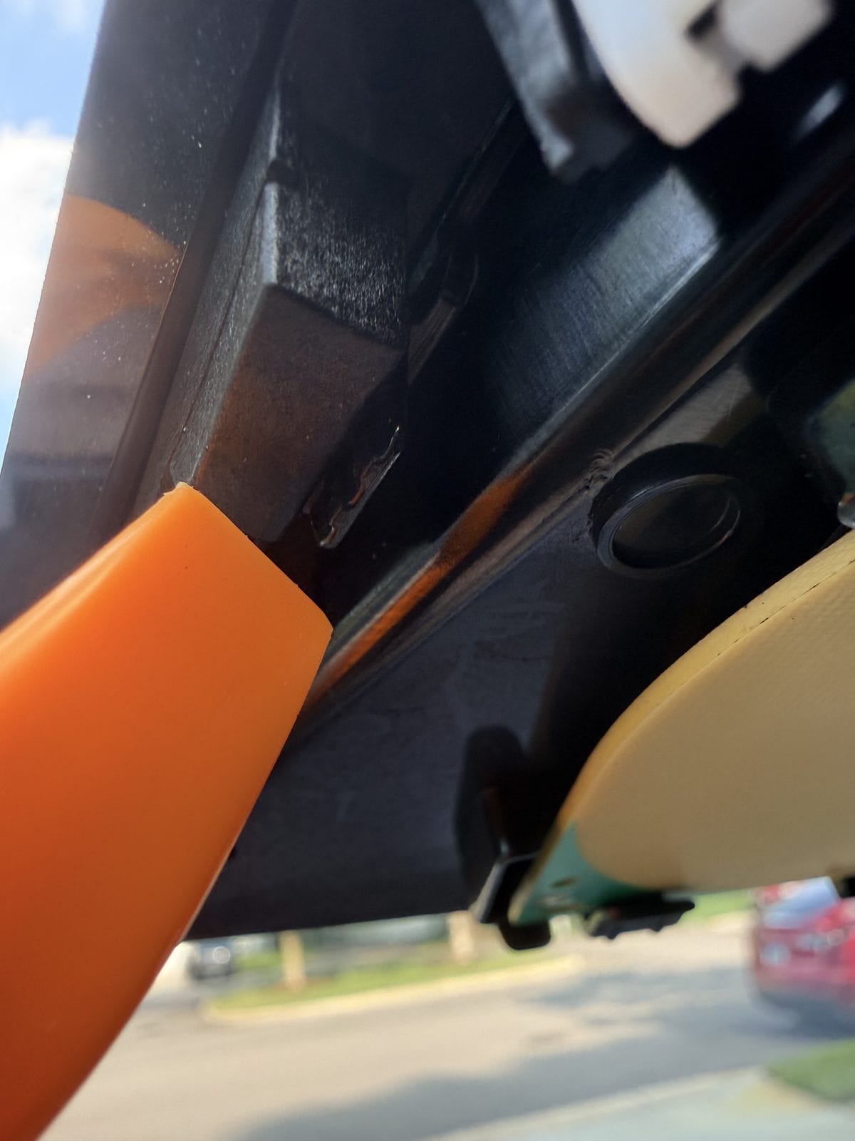 Trim tool pointing to the side clip that releases the Tesla inner camera cover