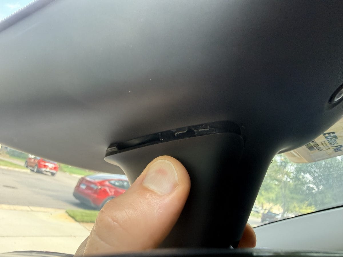 Squeezing the sides of the Tesla mirror-neck cover to release its tension clips