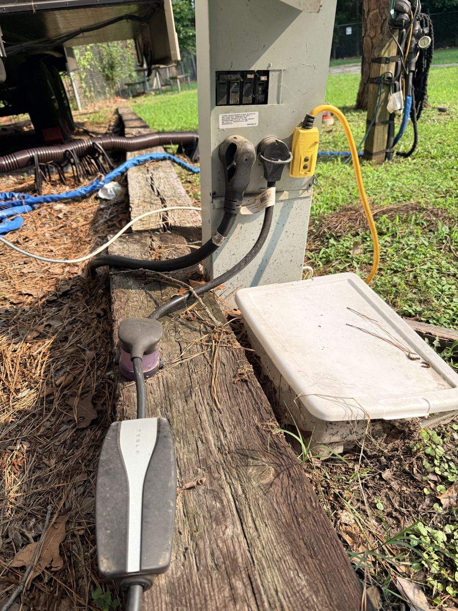 Tesla Mobile Connector with 14-50 adapter connected through a TT-30 to 14-50 adapter in a campground pedestal 30-amp outlet
