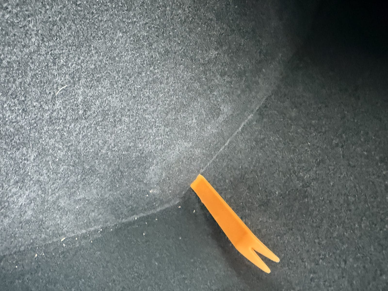 Prying off the Model Y center console side trim with a plastic trim tool