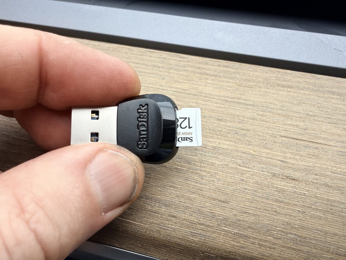 SanDisk High Endurance 128GB microSD card inserted into a small USB reader for Tesla dashcam storage