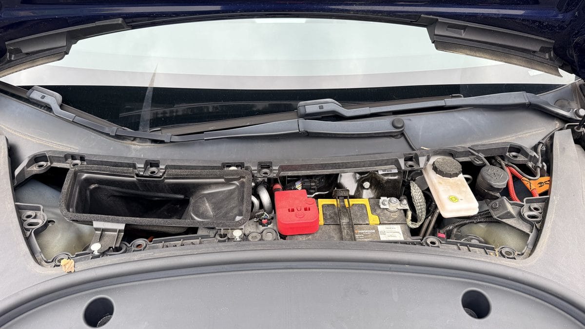 Tesla frunk with maintenance cover removed showing the 12V battery location