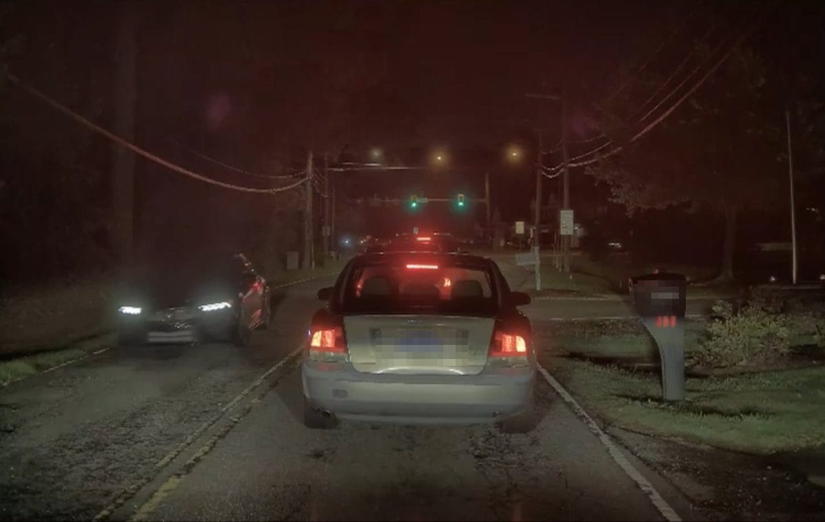 TeslaCam night still showing a legible license plate on a stopped car ahead (plate masked)