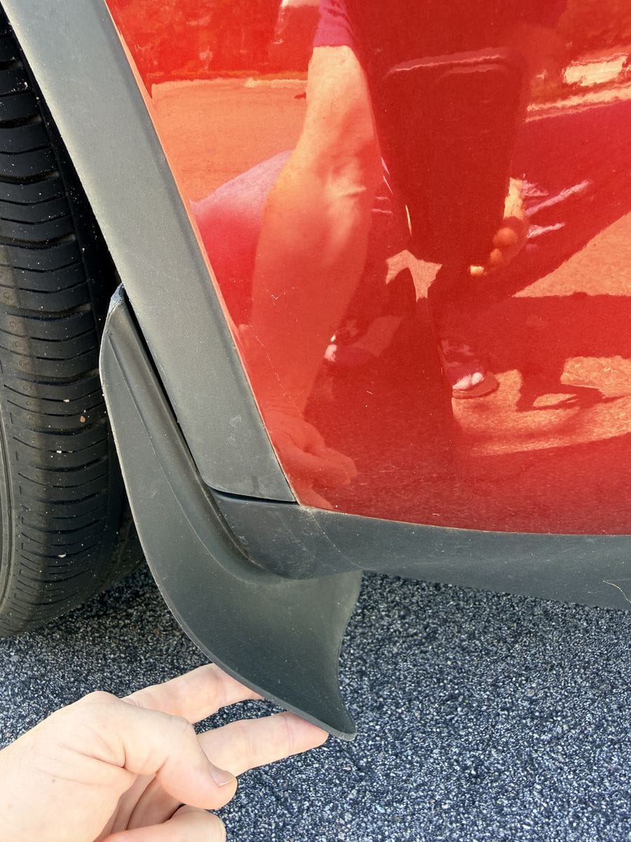 Flexible mud flap on a 2024 Tesla Model Y bent back by hand to show how much it gives